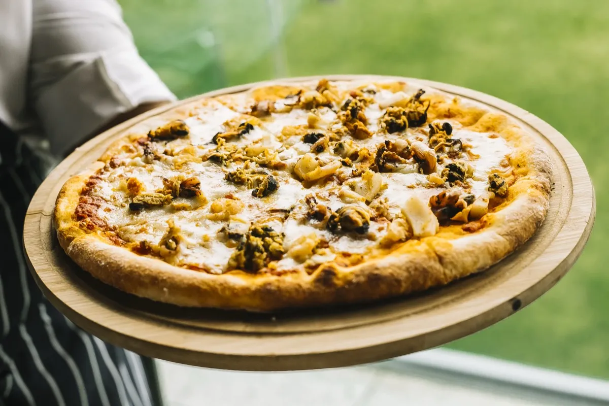 Chef holding seafood pizza